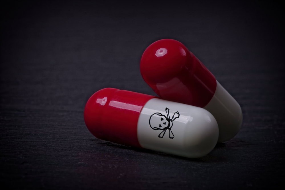 Drug,Capsules,With,Skull,And,Crossbone,On,Dark,Stone,Background.